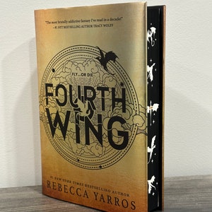 May include: A gold book cover with the title "Fourth Wing" and the text "Fly...or Die" in black. The author's name, "Rebecca Yarros", is printed in black at the bottom of the cover. The book cover has a black spine with white dragon silhouettes.