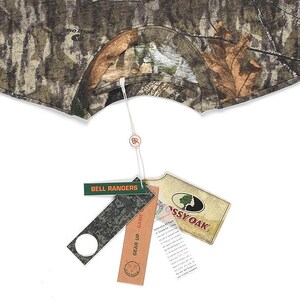 May include: Camouflage pattern garment with tags. The tags include the text "BELL RANGERS", "GEAR UP - GAME", and the Mossy Oak logo. The garment is in shades of brown, green, and tan.