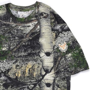 May include: A camouflage-patterned t-shirt with a detailed forest scene print, including trees and foliage. The shirt has a round neckline and short sleeves. A circular patch with the word "Rangers" is on the sleeve.