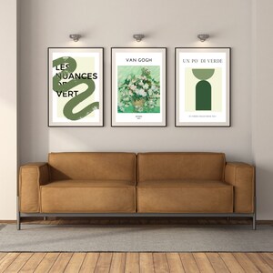 Op de afbeelding: Drie ingelijste kunstprints aan een muur boven een bruine leren bank. De linker print heeft een groen abstract ontwerp met de tekst "Les Nuances de Vert". De middelste print is een schilderij van witte rozen van Van Gogh. De rechter print heeft een groen geometrisch ontwerp met de tekst "Un Po Di Verde".