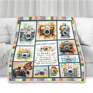 May include: A colorful throw blanket with a patchwork design featuring vintage cameras and the quote "Life is like a camera. Just focus, capture, develop from the negatives, if things don't work out, just take another shot."