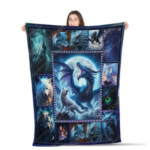 May include: A blue and white fleece blanket with a collage of images of wolves and dragons. The central image features a blue dragon with wings spread wide, roaring at two white wolves. The blanket is framed with a film strip border.