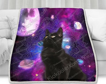 Puede incluir: Un gato negro con ojos amarillos se sienta frente a un fondo de galaxia púrpura y rosa con un diseño de mandala. El gato está mirando hacia arriba a una luna blanca con un brillo rosado.