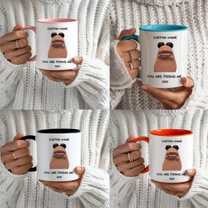 May include: Four white ceramic mugs with different colored interiors and handles: pink, blue, black, and orange. Each mug features a cartoon face, the text "CUSTOM NAME" and "YOU ARE PISSING ME OFF".
