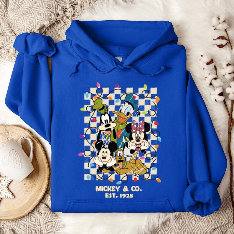 May include: A royal blue hoodie with a graphic of Mickey Mouse, Minnie Mouse, Donald Duck, Goofy, and Pluto surrounded by Christmas lights on a checkered background. The text "Mickey & Co. EST. 1928" is printed below the graphic.