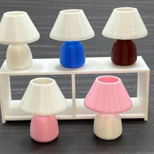 May include: Five miniature table lamps with white lampshades. The lamps have different colored bases: white, blue, red, pink, and white.