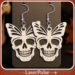 Puede incluir: Un par de pendientes de madera con forma de calavera y detalles de alas de mariposa. Los pendientes son de color marrón claro con un diseño detallado de calavera y ganchos plateados. Se muestran sobre un fondo marrón.