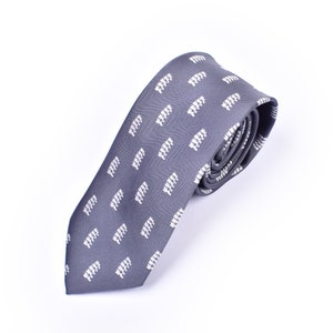 May include: A gray necktie with a white repeating pattern of small figures. The tie is rolled up and ready to be worn.