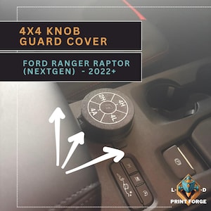 Könnte beinhalten: Eine schwarze 4x4-Knopfschutzabdeckung für einen Ford Ranger Raptor (NextGen) 2022+. Die Abdeckung ist kreisförmig mit weißen Markierungen für die Einstellungen 2H, 4H, 4L und 4A. Das Bild zeigt auch andere Fahrzeugbedienelemente.