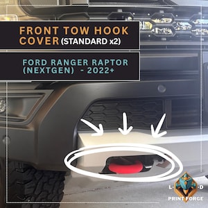 Puede incluir: Primer plano de un parachoques de vehículo negro y plateado con un gancho de remolque rojo. El texto "FRONT TOW HOOK COVER (STANDARD x2)" y "FORD RANGER RAPTOR (NEXTGEN) - 2022+" se muestran en la imagen.