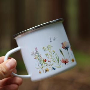 May include: White enamel mug with a floral design and the name "Lia" printed on the side.