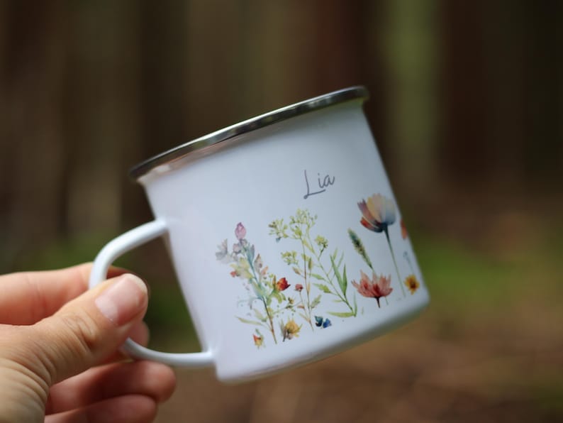 May include: White enamel mug with a floral design and the name "Lia" printed on the side.