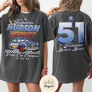 May include: A gray t-shirt with a vintage-style graphic of a blue car with the text "Fabulous Hudson Hornet" and "Piston Cup Champion '51 '52 '53". The back of the shirt has the number "51" and the text "Fabulous Hudson Hornet".