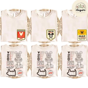 May include: Six cream-colored t-shirts with various Mickey Mouse-themed graphics. Designs include racing-themed badges and a graphic of Mickey Mouse with the text "28" and "Fuel the Magic". The shirts are neatly folded on a woven surface.