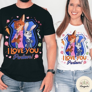Pu&ograve; includere: T-shirt bianche e nere con un design a cartoni animati di volpe e coniglio e la scritta "I Love You Partner!". Il design include uno scudo blu, carote, impronte di zampe e una cravatta.
