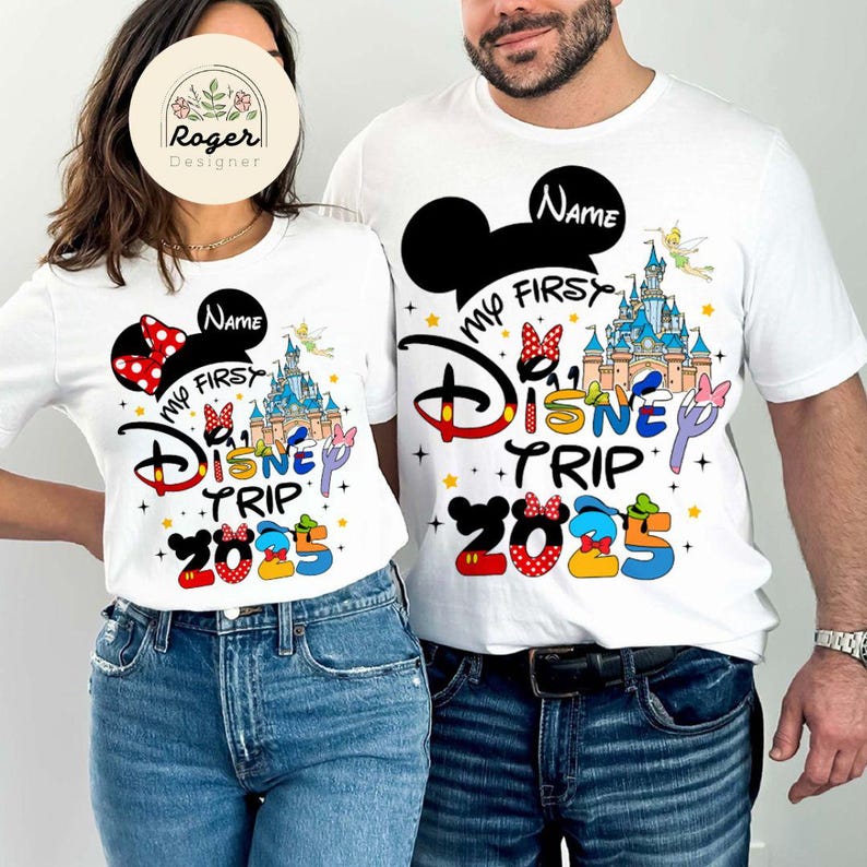May include: White t-shirts with a Mickey Mouse ears design and the text "My First Disney Trip 2025". One shirt has a red bow and the other has a black bow.