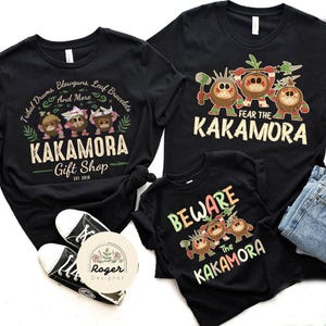Puede incluir: Tres camisetas negras con un dise&ntilde;o gr&aacute;fico de personajes de dibujos animados. Las camisetas para adultos dicen "Fear the Kakamora" y la camiseta para ni&ntilde;os dice "Beware the Kakamora".