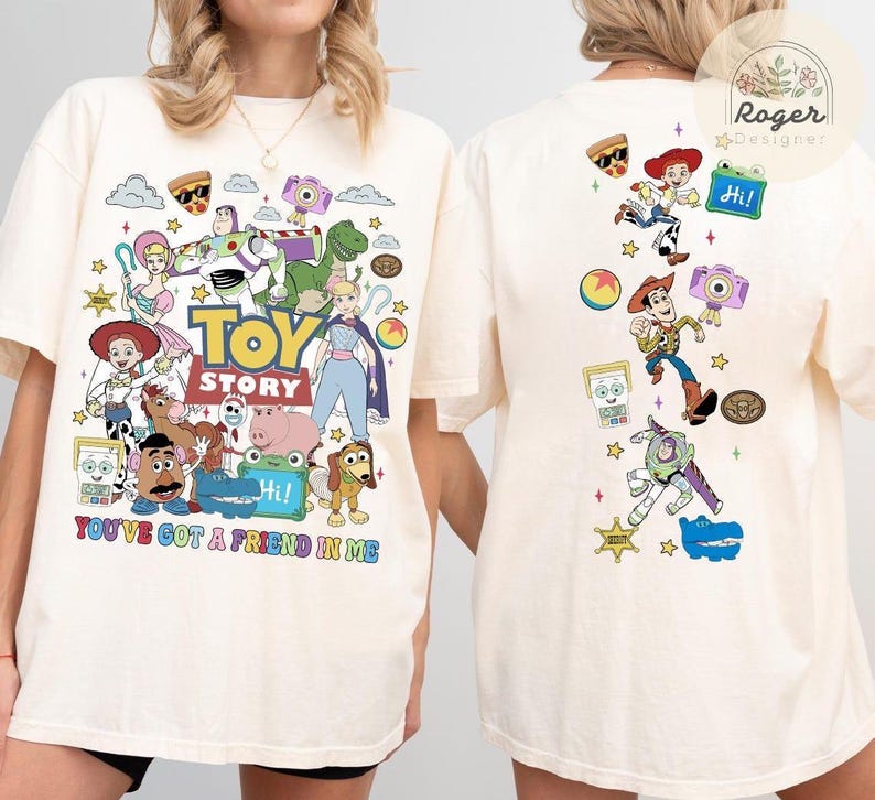 May include: An off-white t-shirt featuring a large graphic print of Toy Story characters on the front and a vertical arrangement of the same characters on the back. The front includes the text TOY STORY and YOU'VE GOT A FRIEND IN ME.