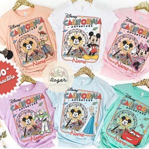 May include: A collection of colorful Disney California Adventure t-shirts. Each shirt features a different Disney character, including Mickey Mouse, Minnie Mouse, Buzz Lightyear, and Lightning McQueen. The shirts are in various colors, including pink, blue, and green.