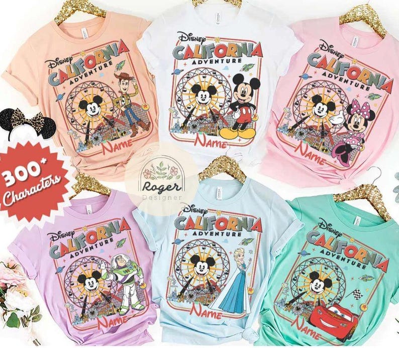 May include: A collection of colorful Disney California Adventure t-shirts. Each shirt features a different Disney character, including Mickey Mouse, Minnie Mouse, Buzz Lightyear, and Lightning McQueen. The shirts are in various colors, including pink, blue, and green.