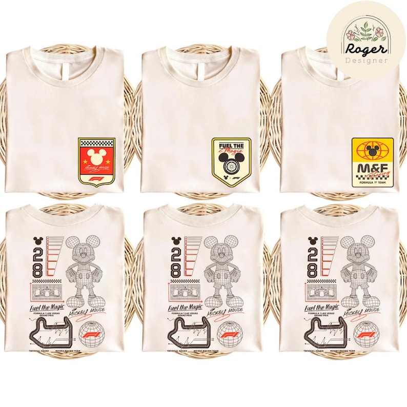 May include: Six cream-colored t-shirts with various Mickey Mouse-themed graphics. Designs include racing-themed badges and a graphic of Mickey Mouse with the text "28" and "Fuel the Magic". The shirts are neatly folded on a woven surface.