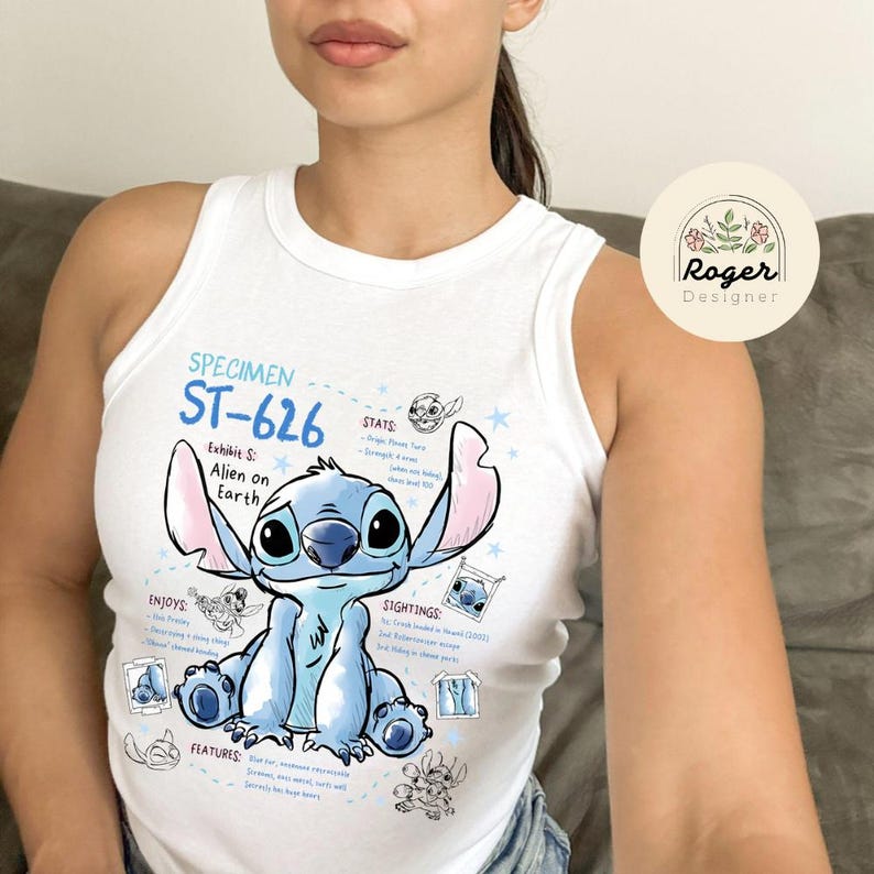 May include: White tank top featuring a blue cartoon alien character, "ST-626", with pink ears and the text "Alien on Earth". The top includes additional graphic elements and text, with a "Roger Designer" logo.