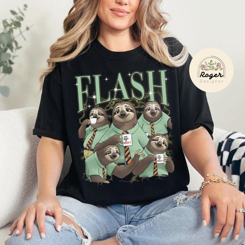 May include: Black t-shirt with a graphic of five sloths wearing green shirts and orange striped ties, holding mugs that read "YOU WANT IT WHEN?". The word "FLASH" is printed above the sloths in green.