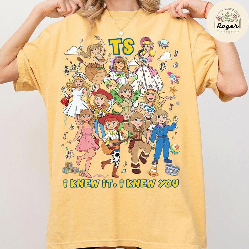 Op de afbeelding: Een geel t-shirt met korte mouwen en een grafische print van meerdere geanimeerde personages in diverse outfits, waaronder een ruimtepak en cowgirl-kleding. De tekst TS staat bovenaan en I KNEW IT, I KNEW YOU staat onderaan.