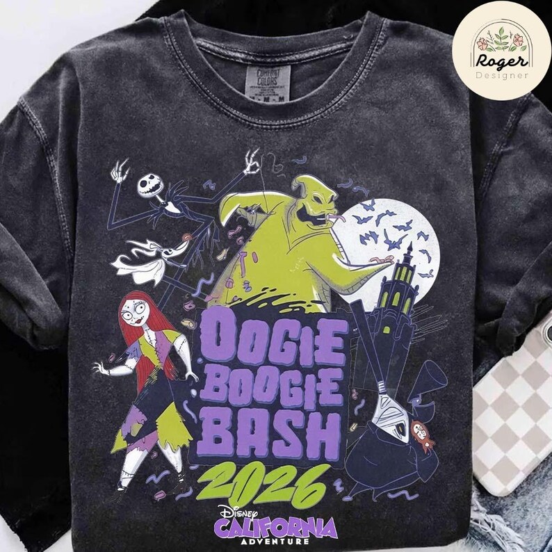 May include: A charcoal gray crew neck t-shirt featuring a graphic print of characters from The Nightmare Before Christmas, including Oogie Boogie, Jack Skellington, Sally, and Zero. The text reads Oogie Boogie Bash 2026 California Adventure.