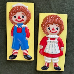 Handmålad väggkonst i keramik från 1974 med Raggedy Ann och Andy