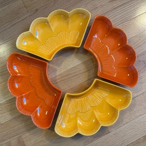 May include: A set of four ceramic serving dishes in a fan shape. Two are a bright yellow, and two are a vibrant orange. Each dish has a scalloped edge and a textured, ridged design.