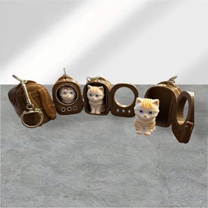 May include: A set of brown backpack-shaped keychains, each featuring a small, light-colored kitten figurine with blue eyes. Some kittens are visible inside the open backpack compartments, while others are positioned outside the cases.