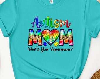 May include: A turquoise blue t-shirt with the text "Autism Mom" in rainbow colors with a puzzle piece heart and the text "What's Your Superpower?"