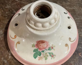 Peut inclure: Un luminaire de plafond en céramique blanche avec une bordure rose et un motif floral représentant une rose rose. Le luminaire est doté d'une douille d'ampoule standard.