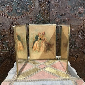 May include: A three-panel antique mirror with a gold frame and a vintage print of a couple in the center panel.
