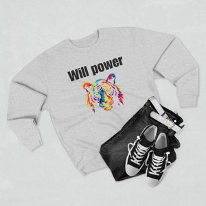 May include: A grey sweatshirt with the text "Will power" printed in black. A colourful tiger illustration is below the text. The sweatshirt is laid out on a white surface with a pair of black trainers and blue jeans.
