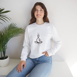 May include: White sweatshirt with a black line drawing of a person in a yoga pose and the text "Keep Calm".