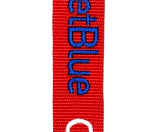 Könnte beinhalten: Roter Gepäckanhänger mit weißem Text "CREW" und blauem Text "JetBlue" und "MCO".
