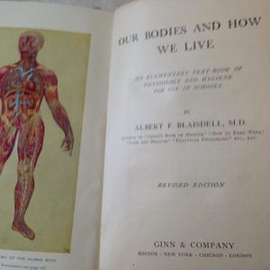 May include: A vintage book titled "Our Bodies and How We Live" by Albert F. Blaisdell, M.D. The book is an elementary text book of physiology and hygiene for use in schools. The cover features an illustration of the human body with internal organs and circulatory system.