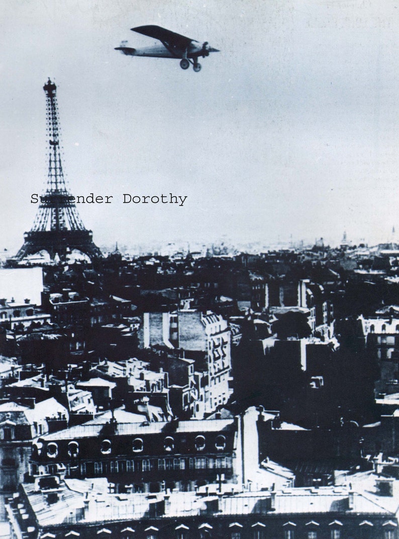 May include: A black and white photograph of the Eiffel Tower in Paris, France. A small airplane flies over the tower. The text "S.ender Dorothy" is printed on the image.