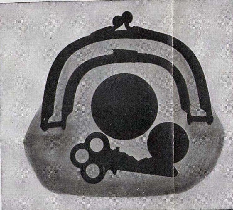 May include: A black and white image of a vintage purse with a key and two circles inside. The purse has a metal clasp and is made of a soft material.