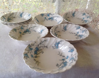 Könnte beinhalten: Satz von acht weißen Keramikschalen mit einem blauen Blumenmuster. Die Schalen haben einen gewellten Rand und eignen sich perfekt zum Servieren von Salaten, Desserts oder Snacks.