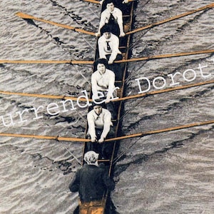 Könnte beinhalten: Eine Gruppe von Menschen rudert in einem Boot auf einem Gewässer. Das Boot wird von fünf Personen gerudert, und hinten sitzt eine Person am Steuer. Das Wasser ist unruhig und das Boot bewegt sich schnell. Der Text "Surrender Dorothy" ist über das Bild geschrieben.