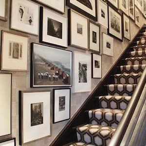May include: A staircase with a patterned carpet in black and white. The wall is decorated with framed artwork in various sizes and styles.