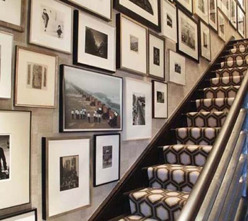 May include: A staircase with a patterned carpet in black and white. The wall is decorated with framed artwork in various sizes and styles.