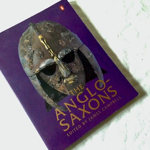 May include: A purple book with a gold title "The Anglo-Saxons" and a picture of a helmet on the cover. The book is edited by James Campbell.
