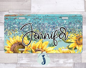 May include: A turquoise blue and white glitter background with a woodgrain texture. The name "Jennifer" is written in black cursive script. The background is decorated with yellow sunflowers.