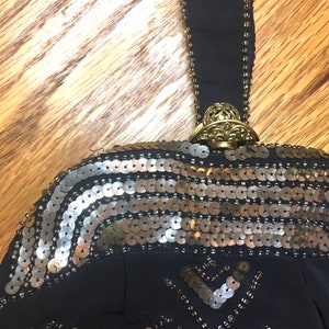 May include: A black beaded evening bag with a gold clasp and a gold and silver sequined design.