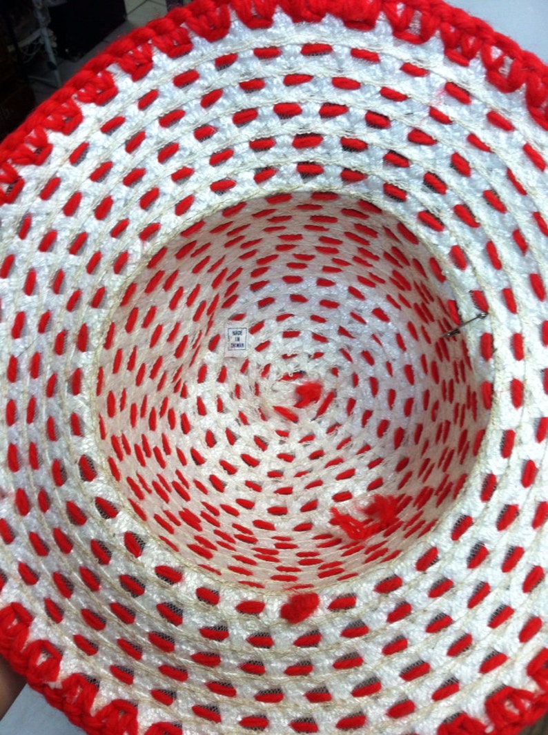 Puede incluir: Un sombrero de crochet blanco y rojo con una etiqueta que dice "Hecho en Taiw&aacute;n".