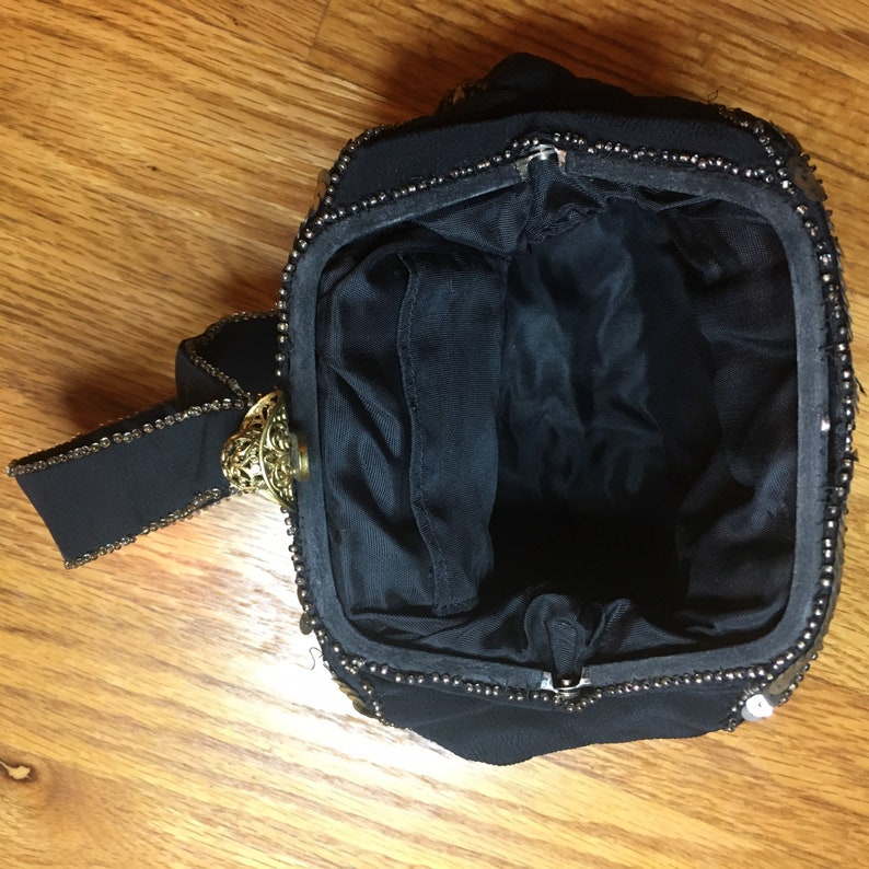 May include: A black beaded evening bag with a gold clasp and a black fabric strap.